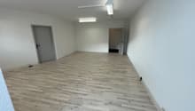 empty room with wooden floor, two doors, and fluorescent ceiling lights