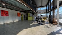 large open space, concrete floor, metal ceiling, large windows, modern furniture, artwork on wall