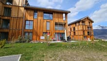 wooden exterior, large windows, balconies, outdoor seating area, green lawn, mountain view