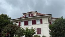 2 story house, white walls, red shutters, red roof, concrete fence, street lamp, trees