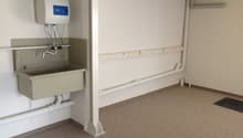 Empty room with a sink, pipes, and a water heater