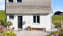 2 story house, wooden exterior, white walls, raised ground floor, garden, bench, mailbox