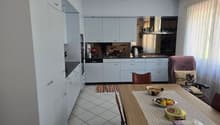 modern kitchen with white cabinets, black countertops, stainless steel appliances, dining table with decorative items