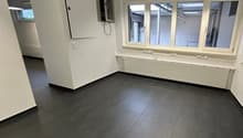 empty room, white walls, tiled floor, large windows, radiator, wiring equipment in corner
