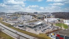 Building complex, multiple buildings, large parking lot, highway in front, green surroundings