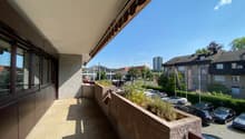 elevated balcony with large planter, railings, cars parked in lot below