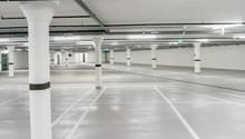 wide parking area, multiple columns, painted white lines, yellow markings, several pipes