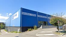 Large blue and white building with the sign 'Carrel Quincaillerie Outillage' indicating it is a hardware and tools store. There is a parking area in front of the building.