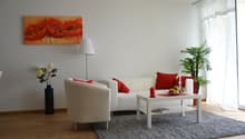 Living room, white couch, red pillows, armchair, floor lamp, coffee table, decorative items, window with curtains