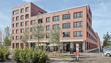 Multi-story brick building with large windows, balconies, and ground-floor commercial spaces including a lounge bar and cafe.