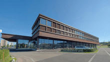 modern office building, large glass facade, brown facade, large parking lot, cars parked in front