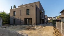 Modern house, brown wooden exterior, large windows, balcony, under construction