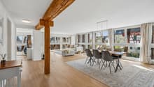 open living room with dining area, large windows, wooden floor, wooden beam, table, chairs, rug, side table, couch, coffee table, pillows