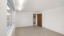 Empty room with white walls, tiled floor, large window, open door leading to another room