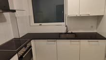 modern kitchen with black counter tops, electric stove, built-in oven, sink, and a window