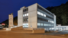 3 story office building, white walls, glass windows, front parking lot, blue signs, street light