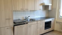 A kitchen with wooden cabinets, granite countertops, a sink, oven, dishwasher, and a window.