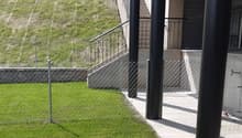small fenced yard with short manicured lawn, stone retaining wall, black balustrade with metal railings