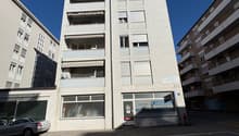 modern white building with 4 floors, balcony, car parked in front, ground floor commercial space