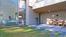 modern house, large glass windows, outdoor dining area, potted plant, grassy lawn