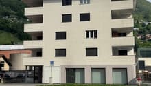 4 story building, white exterior, multiple windows, parking area in front