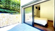 bedroom with bed, sliding glass door, wooden floor, stone wall, outdoor view