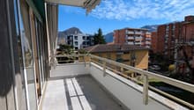 large balcony with tiled floor, metal railings, retractable awning, view of mountains