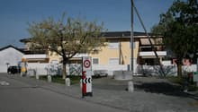 Yellow building with white fence, trees, benches, and a speed limit sign
