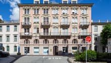 Large building with arched windows, decorative balconies, arched entryway, multiple floors, pink exterior, arched doors, central courtyard area