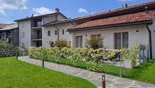 2 story building, brick roof, solar panels, balconies, windows, walkway, grass, fence, plants