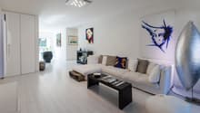 white walls, white floor, white sofa, black coffee table, art pieces on the wall