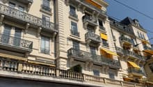 A multi-story building with many balconies, yellow awnings, and a classical architectural style