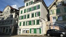 3 story building, white exterior, green shutters, cobblestone street, parked car