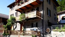 3-story house, wooden balconies, white windows, wooden gate, satellite dish, satellite antenna, garden