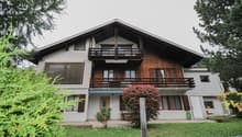 2 story house, wooden trim, white walls, balcony, shrubs, garden, and a tree in front
