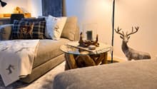 living room with couch, coffee table, desk, lamps, and a deer statue