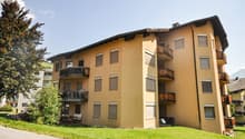 Three story yellow building, modern design, multiple balconies with tables and chairs