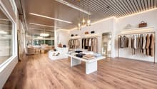 modern interior design, wooden floor, white walls, clothing racks, display tables, lamps