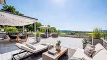 Outdoor terrace with a dining table, chairs, lounge chairs, a coffee table, a canopy, and potted plants.