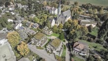 Multiple residential buildings, green roofs, garden areas, church, large open field, roads