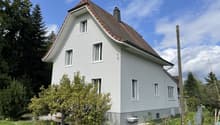 2 story house, white exterior, brown roof, large windows, front yard with greenery