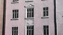 3 story building, pink walls, multiple windows, centered door