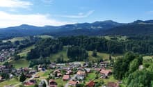 Cluster of houses in a green valley with mountains in the background