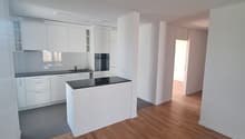 modern kitchen with white cabinets, black countertops, wooden floors, built-in oven and sink