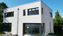 Modern 2-story house, white exterior, large windows, glass doors, trees in the background