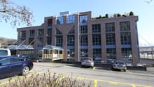 office building, 4 floors, parking lot, trees, shrubs, blue sky