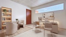 modern office with white walls, white tile flooring, wooden desk, white chairs, wooden bookshelf, plants, monitor, lamp, rug