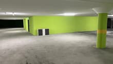 Empty parking area with green walls, concrete floor, column, two small doors, and two cabinets.