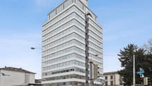 High-rise office building with glass facade, multiple floors, modern architecture, located in an urban area
