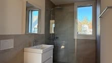 modern bathroom with white toilet, sink, shower, mirror, and tiled floor